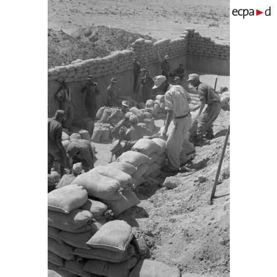 Construction d'un casernement avec des sacs de sable et une toile de tente.