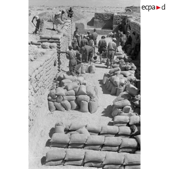 Construction d'un casernement avec des sacs de sable et une toile de tente.