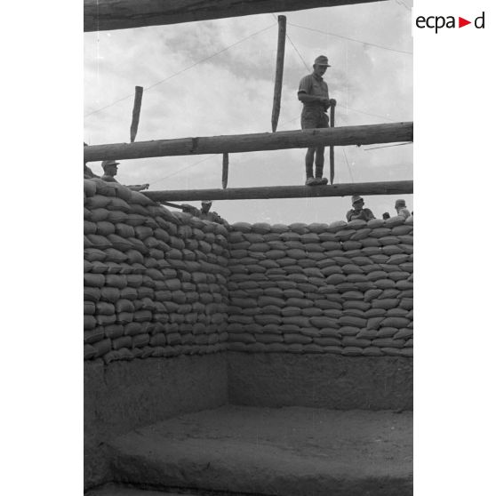 Construction d'un casernement avec des sacs de sable et une toile de tente.