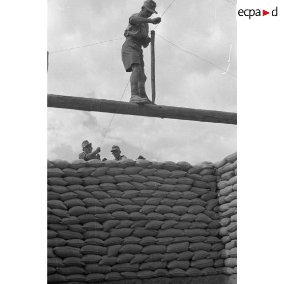 Construction d'un casernement avec des sacs de sable et une toile de tente.
