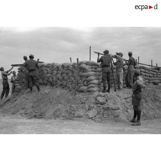Construction d'un casernement avec des sacs de sable et une toile de tente.