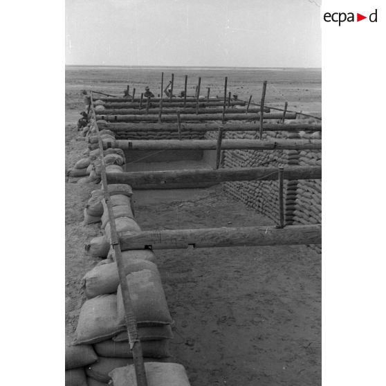 Construction d'un casernement avec des sacs de sable et une toile de tente.