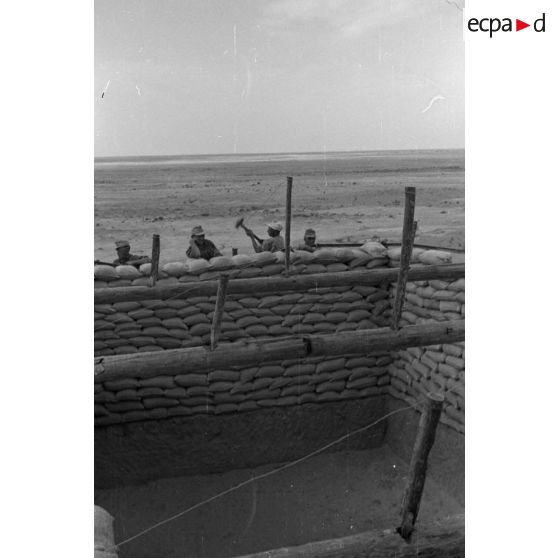 Construction d'un casernement avec des sacs de sable et une toile de tente.
