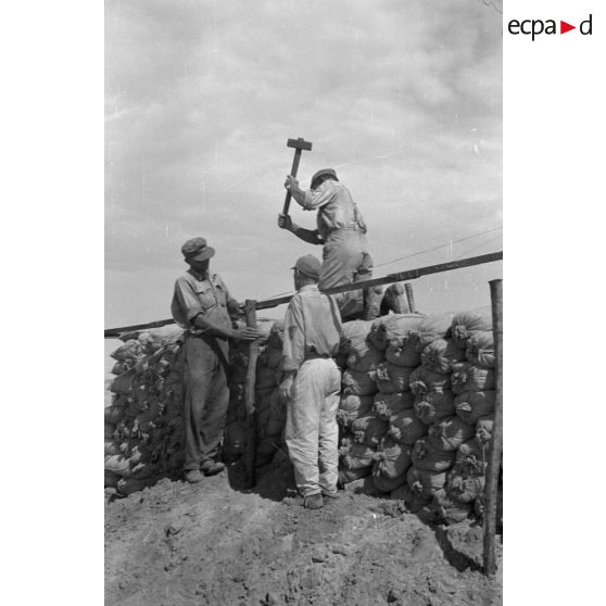 Construction d'un casernement avec des sacs de sable et une toile de tente.