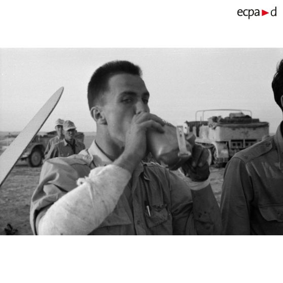 Un autre membre d'équipage de l'avion abattu, prisonnier et blessé au bras, boit l'eau d'une gourde offerte par des soldats allemands.