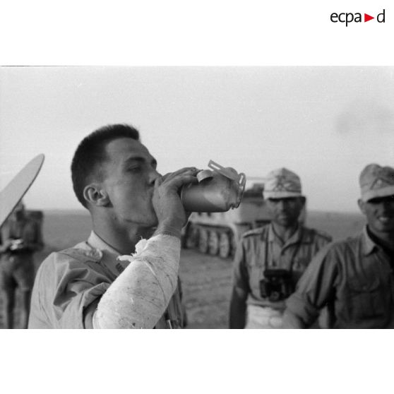 Un autre membre d'équipage de l'avion abattu, prisonnier et blessé au bras, boit l'eau d'une gourde offerte par des soldats allemands.