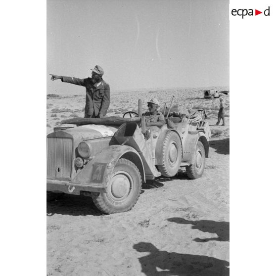 Un Leutnant appartenant à la Pk.Afrika désigne un point debout dans une voiture Kfz-15.