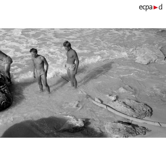 En vue de la désalinisation de l'eau de mer, transport du lest d'un des tuyaux sur un canot pneumatique.