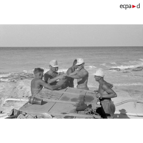 Réparation d'une pièce de la pompe à eau par un groupe de soldats.