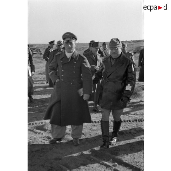 Les maréchaux Cavarello et Rommel gagnent l'abri d'une tente suivis d'officiers allemands et italiens.