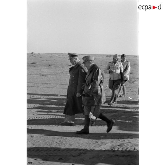 Les maréchaux Cavarello et Rommel gagnent l'abri d'une tente suivis d'officiers allemands et italiens.