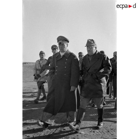 Les maréchaux Cavarello et Rommel gagnent l'abri d'une tente suivis d'officiers allemands et italiens.