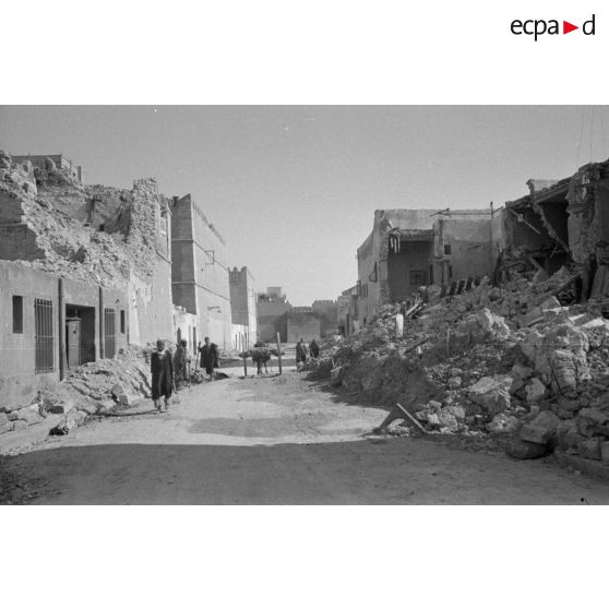 Les rues de Sfax couvertes de débris et bordées de maisons en ruine.