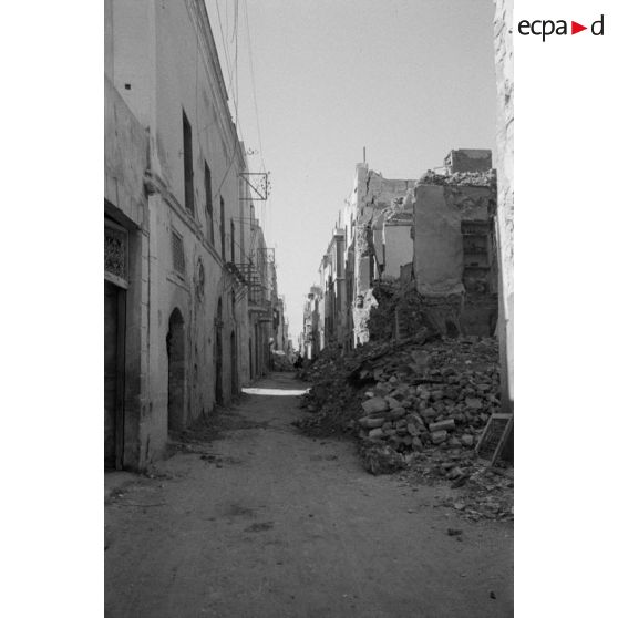 Les rues de Sfax couvertes de débris et bordées de maisons en ruine.