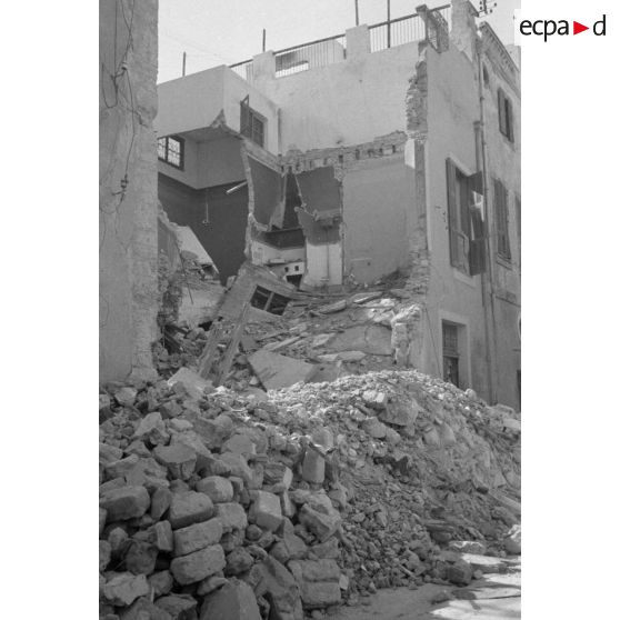 Les rues de Sfax couvertes de débris et bordées de maisons en ruine.