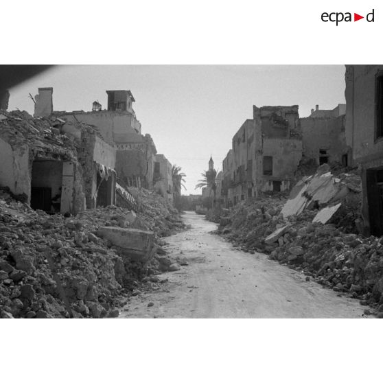 Les rues de Sfax couvertes de débris et bordées de maisons en ruine.