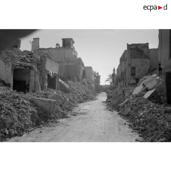 Les rues de Sfax couvertes de débris et bordées de maisons en ruine.