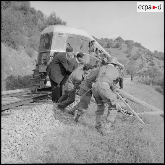 Un train à l'arrêt près du barrage Ighil-Emda. Des soldats et la population dégagent la voie.