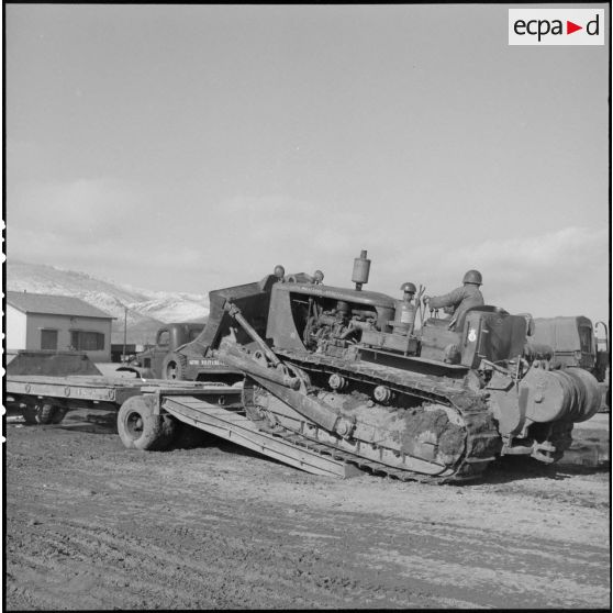 Remorquage d'un tracteur-niveleur Caterpillar par un soldat du 3 régiment étranger d'infanterie à Arris (Aurès).