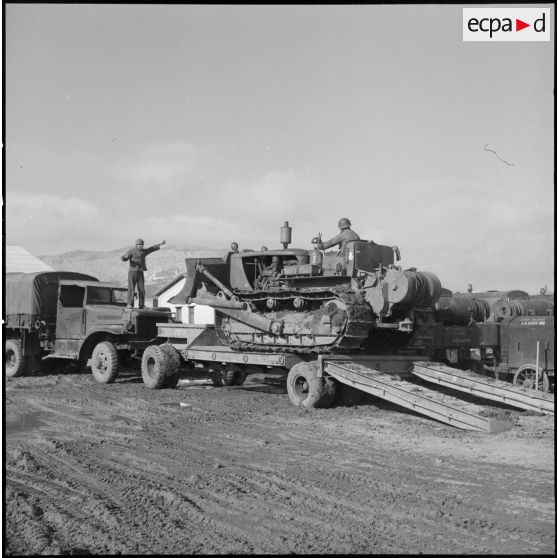 Remorquage d'un tracteur-niveleur Caterpillar par un soldat du 3 régiment étranger d'infanterie à Arris (Aurès).