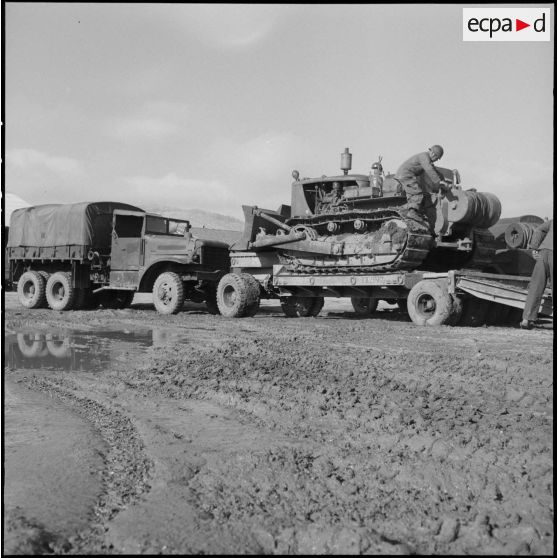Remorquage d'un tracteur-niveleur Caterpillar par un soldat du 3 régiment étranger d'infanterie à Arris (Aurès).