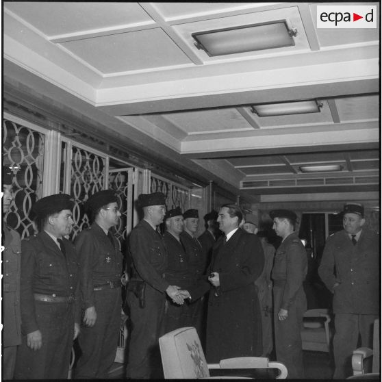 Poignée de main entre un officier du 21e régiment d'infanterie coloniale (RIC) et le secrétaire d'Etat des forces armées Max Lejeune dans le port d'Alger.