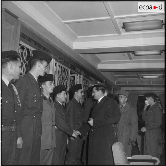 Poignée de main entre un officier du 21e régiment d'infanterie coloniale (RIC) et le secrétaire d'Etat des forces armées Max Lejeune dans le port d'Alger.