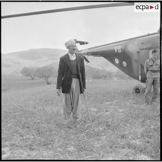 Portrait d'un villageois d'un groupe d'autodéfense de la région de la Soummam devant un hélicoptère Sikorsky H 19 du GH 2 (Groupe d'hélicoptères 2).