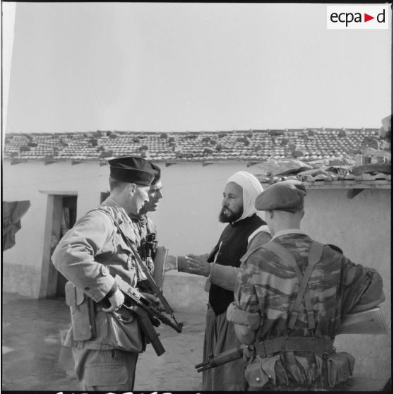 Interrogatoire d'un homme algérien dans la cour d'une mechta par des soldats du 2e BZ (bataillon de zouaves) et du 1e REP (régiment étranger de parachutistes) près d'Aïn Temouchent.