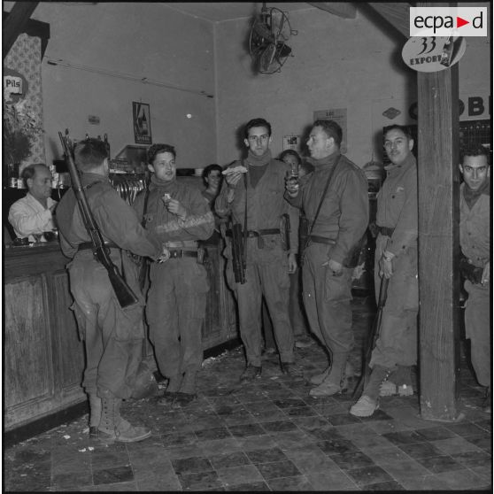 Moment de détente dans un café bar pour des rappelés du Service cinématographique des Armées (SCA) après une patrouille de nuit à Alger.