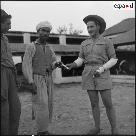 Un soldat de la 20e DI offrant une cigarette à un employé de la ferme Bastos.