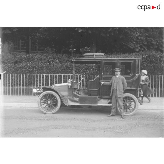 [Chauffeur posant près d'une voiture.]