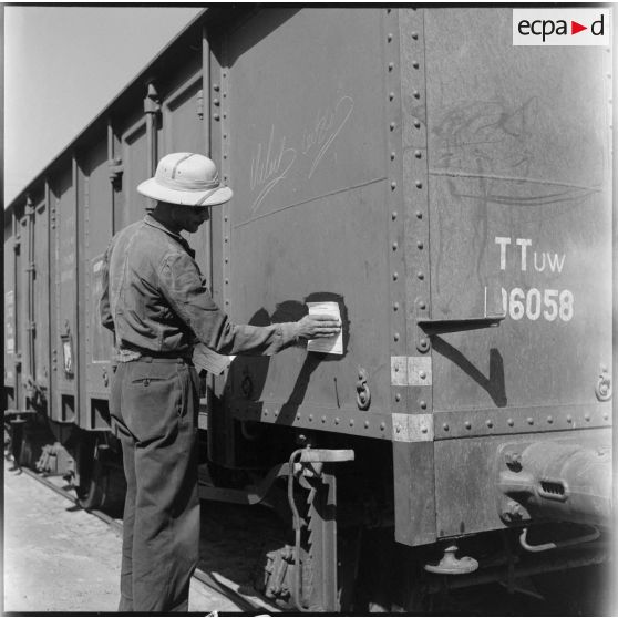 Un homme apposant un papier avec la destination du train sur un des wagons.