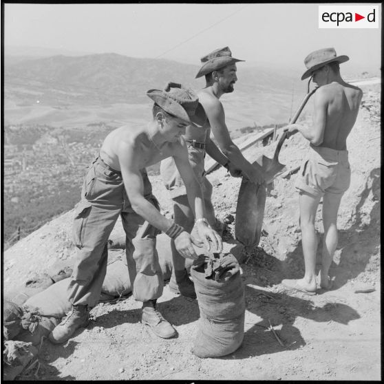 Des soldats de la 1re compagnie du 45e BIC remplissant des sacs de terre.