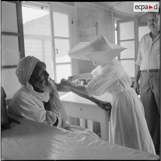 La Mère supérieure des Soeurs de Saint-Vincent de Paul faisant une piqûre à un homme âgé.