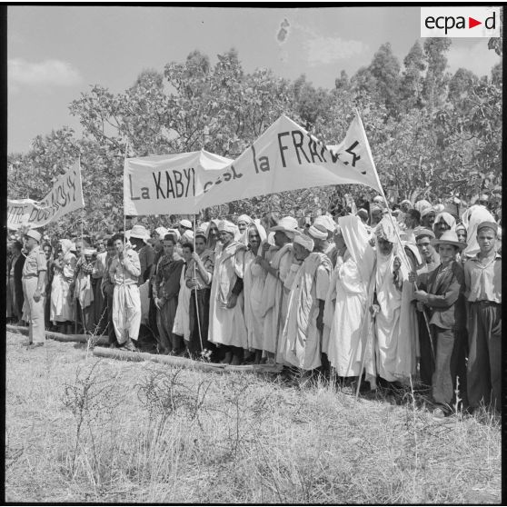 Portant des calicots couverts d'inscriptions patriotiques, les habitants du douar Mechtrass, rassemblés, attendent la revue du général Olié.