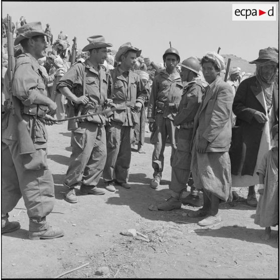Un groupe de spahis discute avec deux supplétifs algériens (en uniforme) et un membre du groupe d'autodéfense.