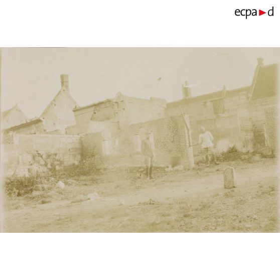 [Deux soldats posant au milieu d'un village en ruines, s.d.]