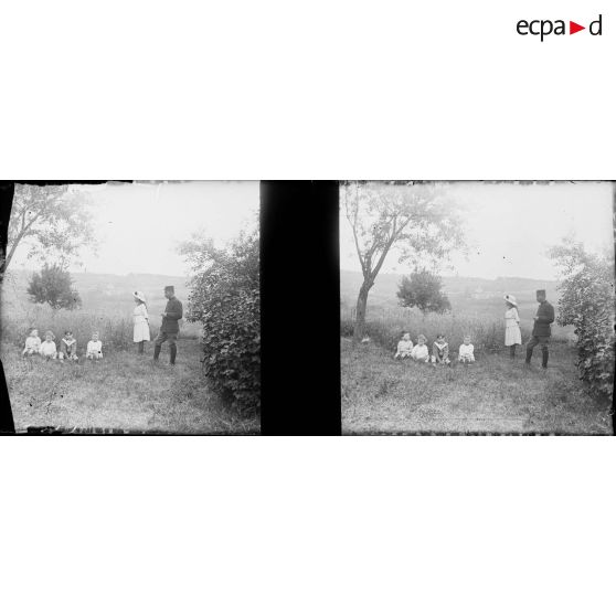 [Enfants assis dans l'herbe surveillés par une jeune fille et un soldat, s.d.]