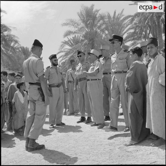 Au cours de sa visite de l'oasis de M'Doukal le général Vanuxen discute avec les officiers qui l'entourent.<br>