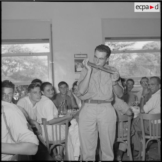 Le brigadier-chef Roger Roux joue de l'harmonica pendant le déjeuner.