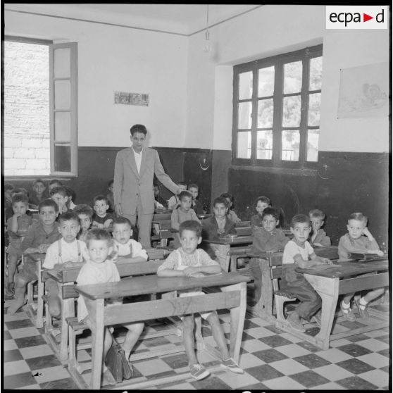 L'instituteur pose avec ses élèves dans la salle de classe.