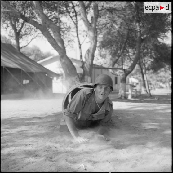 Au camp du Lido à Hussein Dey, sur le terrain d'entraînement, un jeune appelé traverse un tuyau.