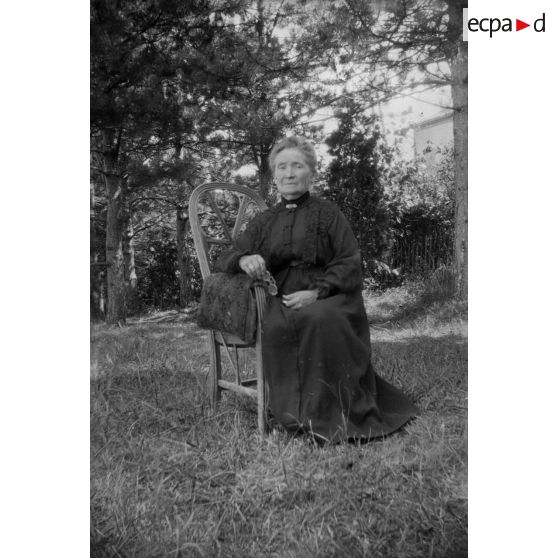 [Portrait d'une femme assise sur un fauteuil dans un jardin, s.d.]