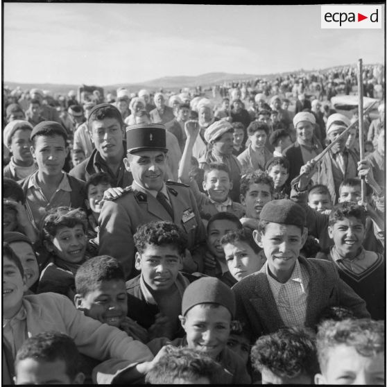 Le capitaine Viltard de la Compagnie de haut-parleurs et de tracts (CPHT), entouré d'enfants lors d'une mission d'action psychologique à Guelma (Nord Constantinois).