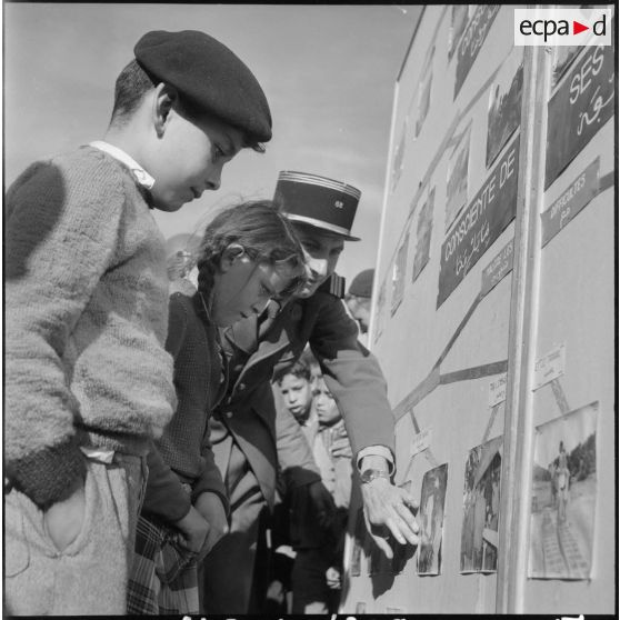 Le capitaine Pasciuto de la CPHT (compagnie de haut-parleurs et de tracts) montrant des panneaux photographiques, dans le cadre de l'action psychologique, à des enfants de Guelma.