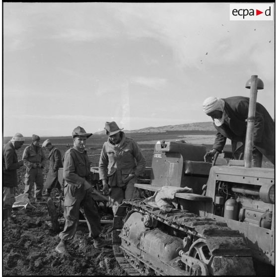 Des soldats du 9e régiment de tirailleurs algériens (BTA) aident à la réparation d'un tracteur lors de leur mission de surveillance des semailles, près d'Aumale (actuelle wilaya de Médéa).