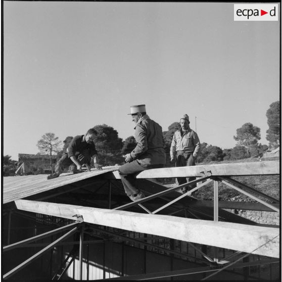 Trois éléments 5e bataillon de tirailleurs algériens (BTA) le toit d'un hangar en chantier à Aïn Terzine.