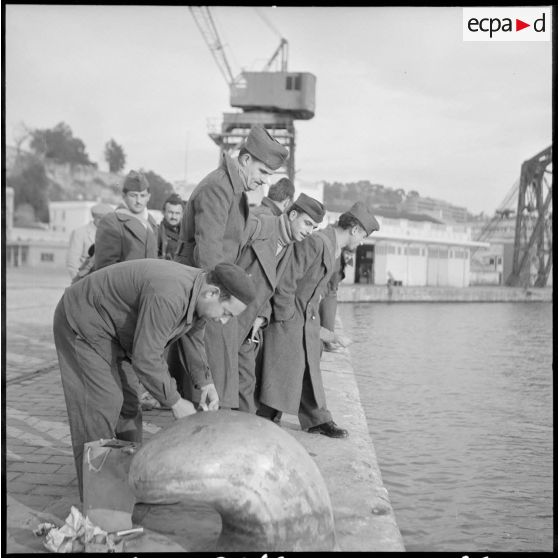 Un employé du port de Bône et un groupe de rappelés avant l'embarquement à bord du Président de Cazalet.