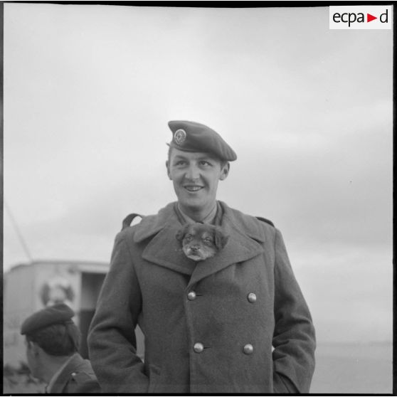 Portrait d'un jeune parachutiste et son chiot sur le port de Bône avant d'embarquer à bord du Président de Cazalet.